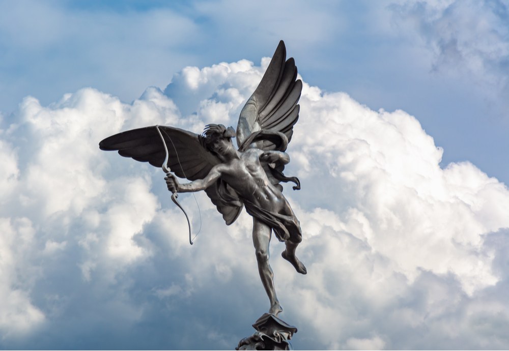 Eros statue A statue of Eros, Cupid's Greek counterpart, shooting an arrow with clouds and a blue sky in the background.