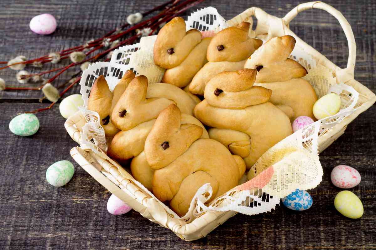 Easter bunny bread A basket of fresh baked Easter bread in the shape of bunny rabbits in a white serving tray on a doily, with robins egg candies arranged around the tray.