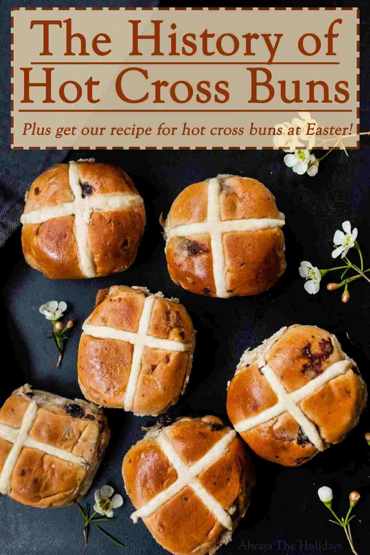 The History of Hot Cross Buns Six hot crossed buns on a black cloth with small white flowers around them and a text overlay above them that reads "The history of hot cross buns plus get our recipe for hot cross buns at Easter".