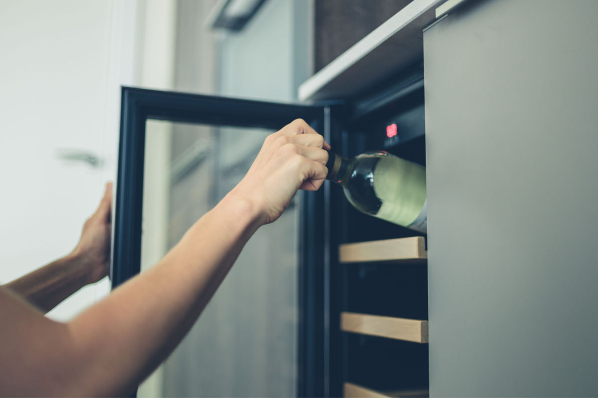 White wine in a wine fridge A bottle of white wine at the perfect temperature for storing white wine being pulled out of the top shelf of a wine fridge.