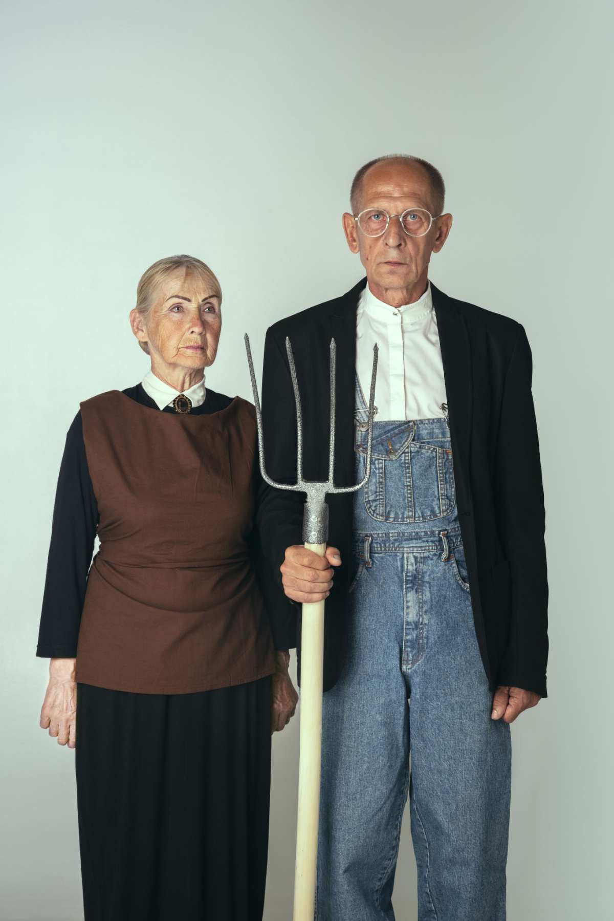 American Gothic Costume ideas An American Gothic costume idea, where the woman is wearing a black dress, with brown vest, and the man is wearing overalls, a white shirt, and suit jacket, and he's holding a pitch fork.