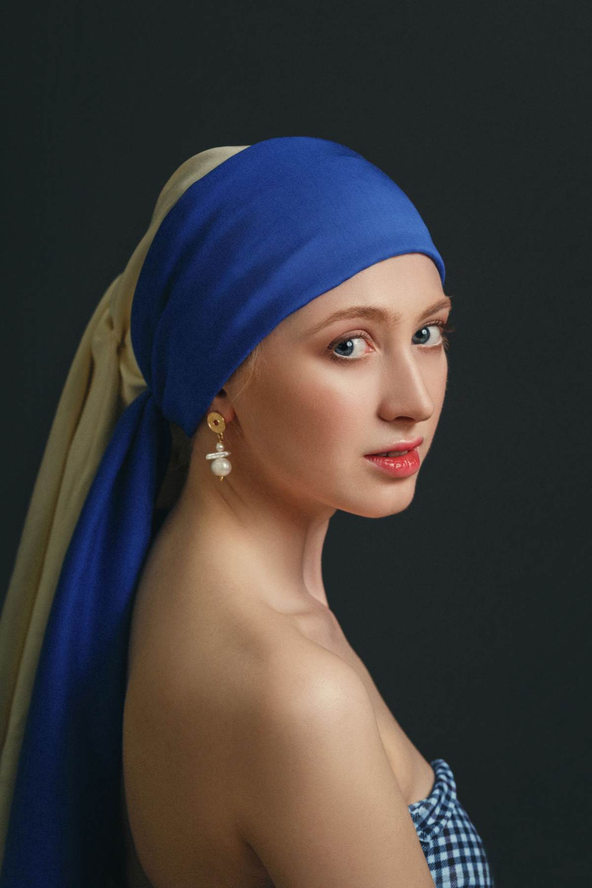 Girl with a Pearl Earring costume DIY A young woman wearing a girl with the pearl earring costume with a blue and white head scarf, a single pearl earring and a blue and white sleeveless top.