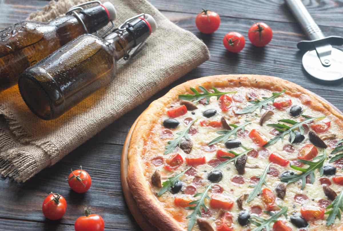 Pizza and beer day Cooked pizza with bottles of beer on a table.