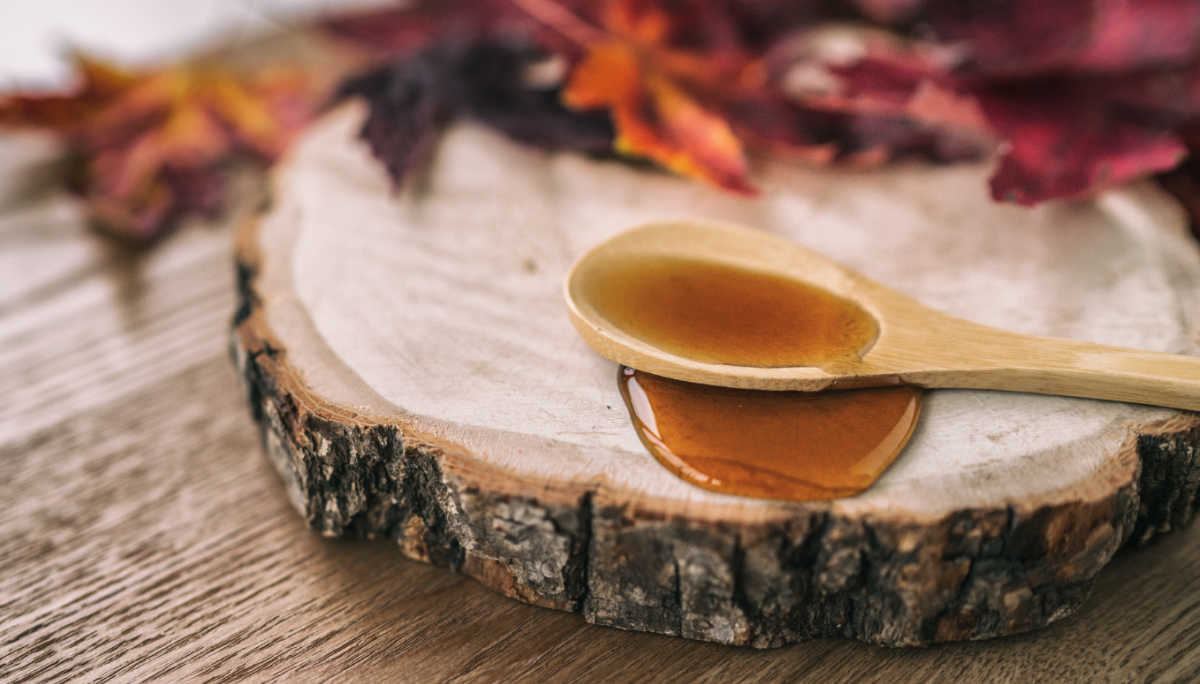 Maple syrup day Maple syrup and spoon on a wooden slab with some maple leaves.