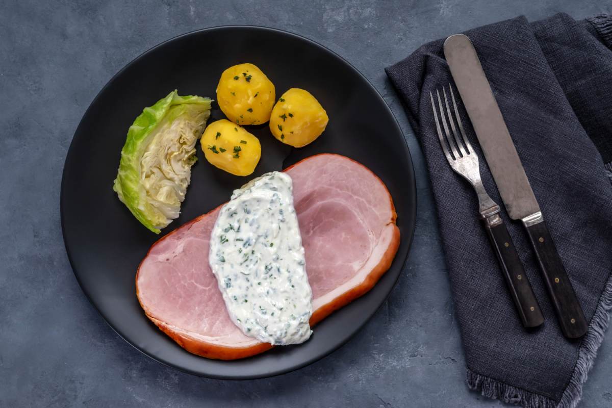 Traditional Irish food, bacon and cabbage A plate of traditional Irish food consisting of bacon and cabbage with a parsley sauce and potatoes beside it on the plate.