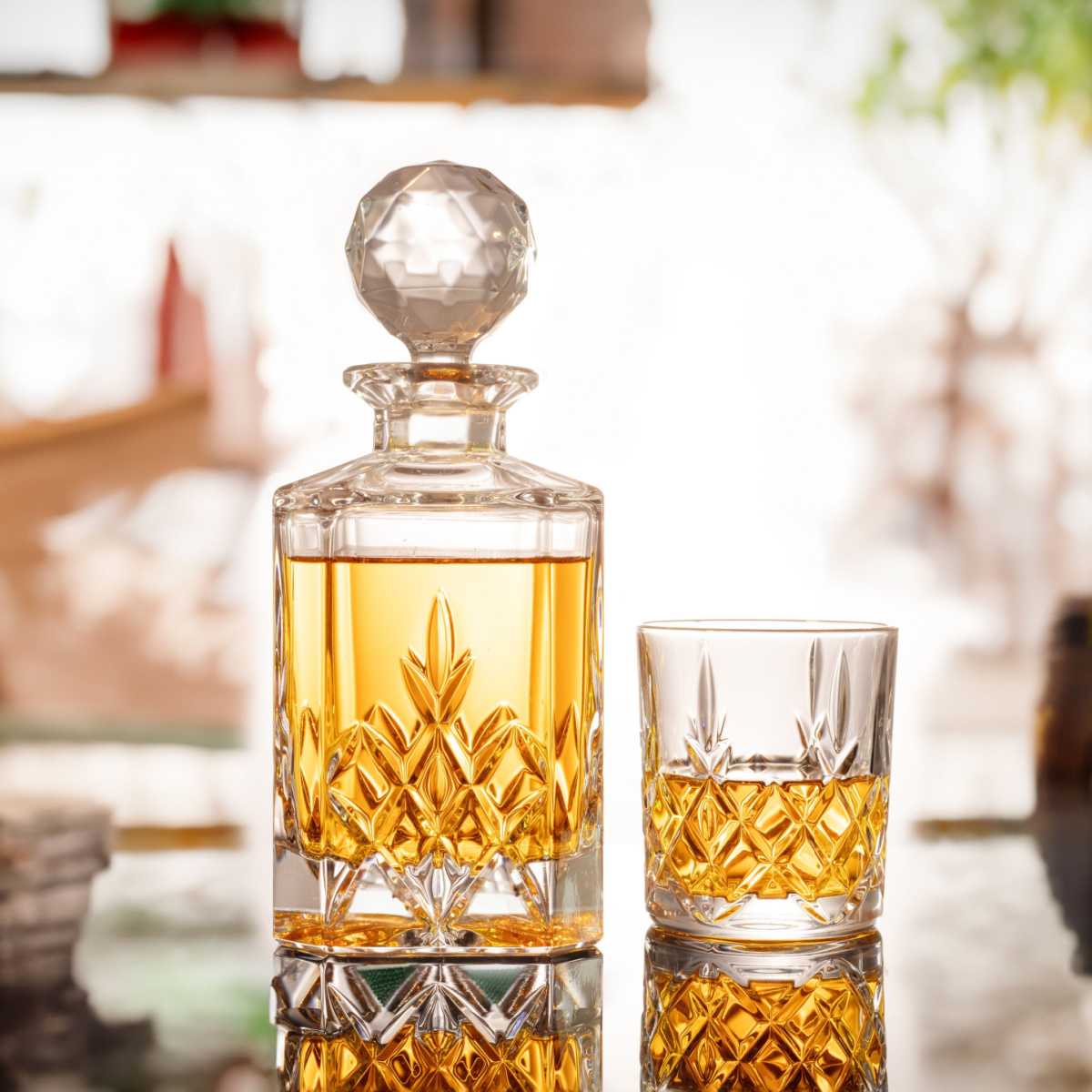 Gold rum A glass decanter of gold rum sitting on a table next to a rocks glass with a pour of rum in it.