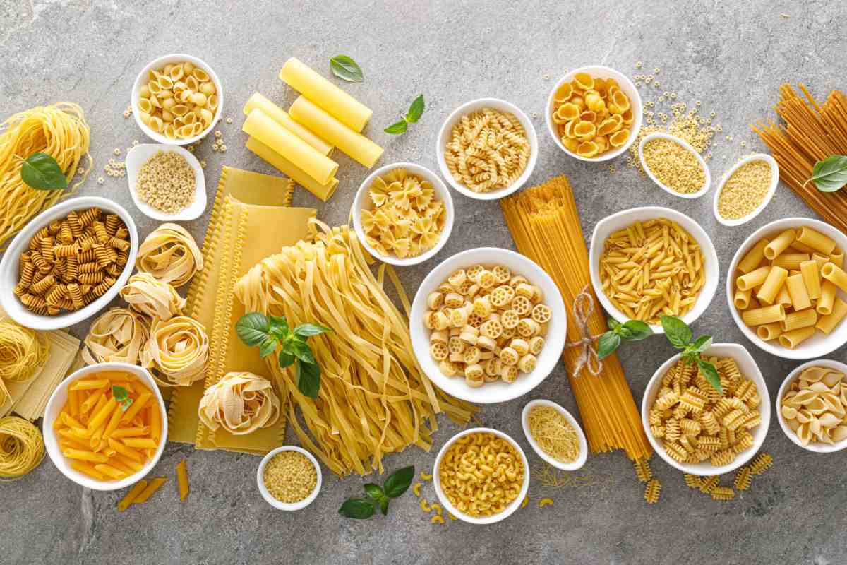 Various dried types of pasta An overhead view of various different types of pasta in bowls, and loose on a marble counter top to celebrate World Pasta Day.