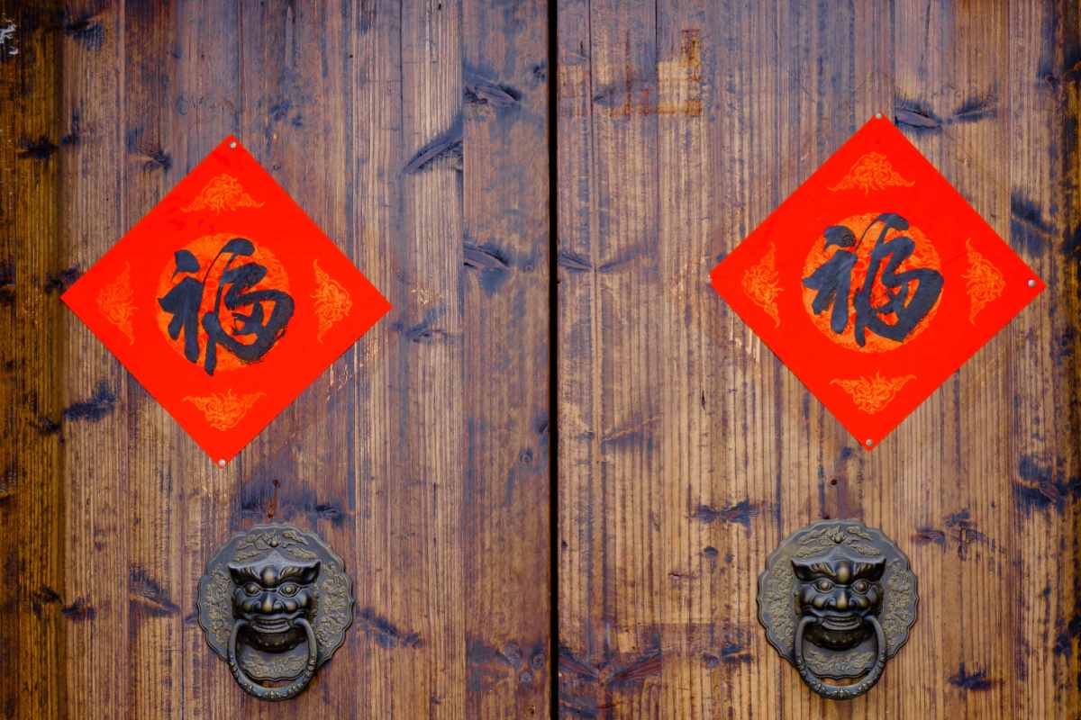 Fu character Two doors with brass door knockers on them, with two red diamonds hanging above them, with the fu character calligraphed on them.