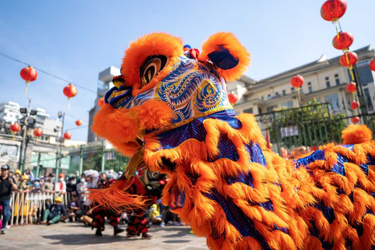 Chinese New Year lion dance A blue and yellow Chinese New Year lion dance costume in the foreground of a Spring Festival celebration, with Chinese New Year lanterns hanging in the background.