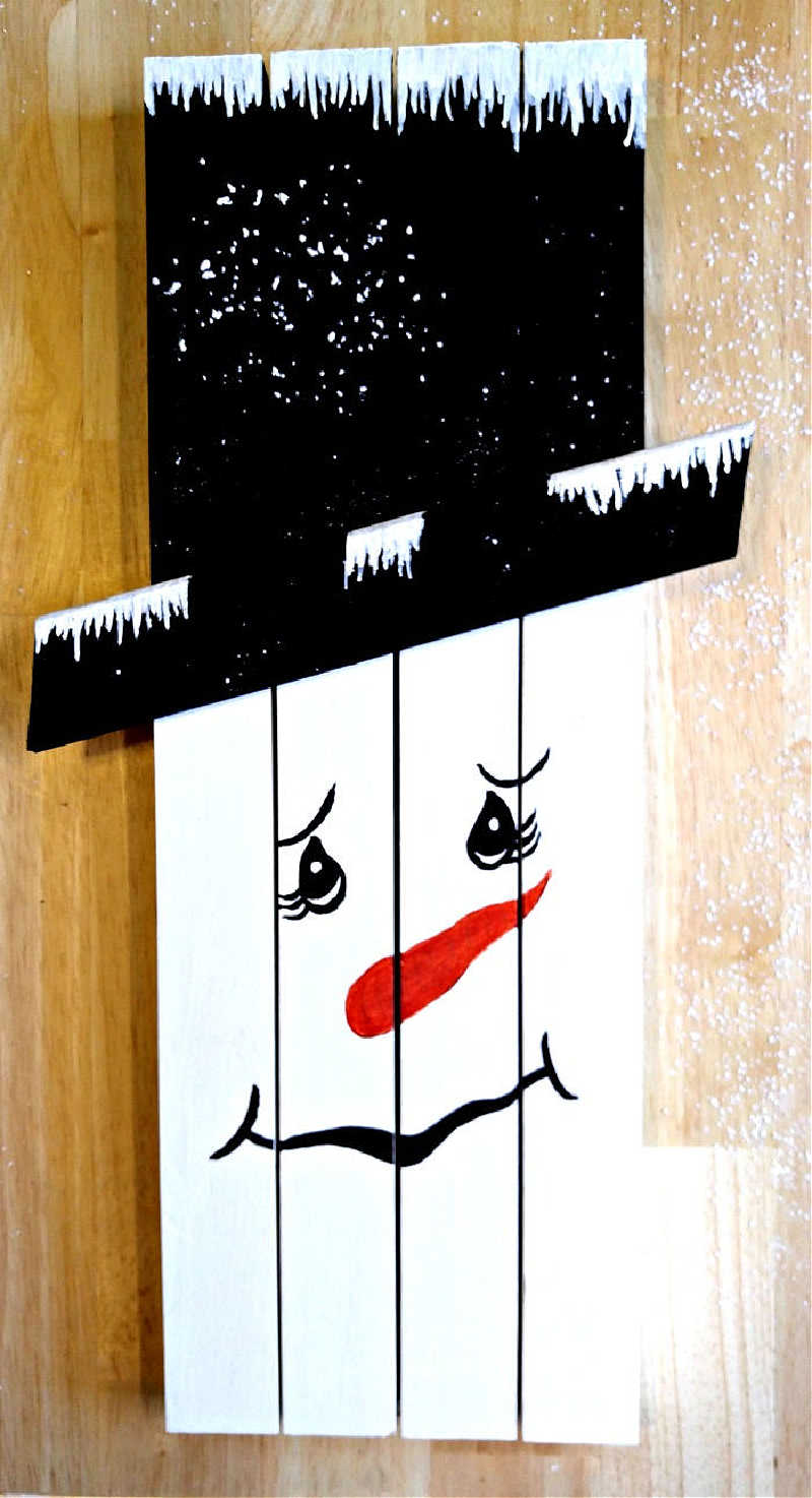 Wooden snowman made from pieces of scrap wood. Wood is painted in white and black.