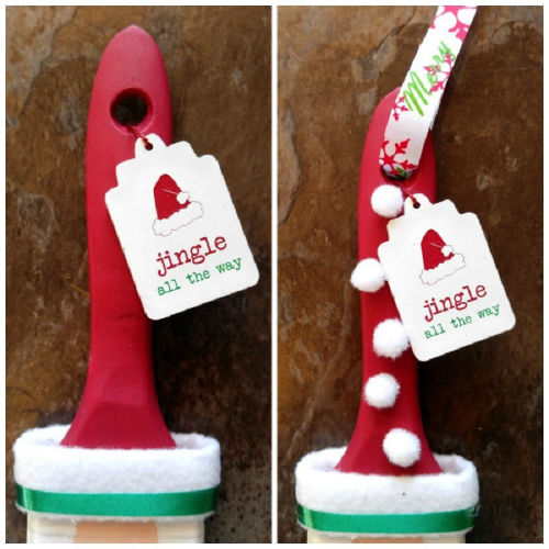 Paint brush decorated with white pom poms and a wooden gift tag.