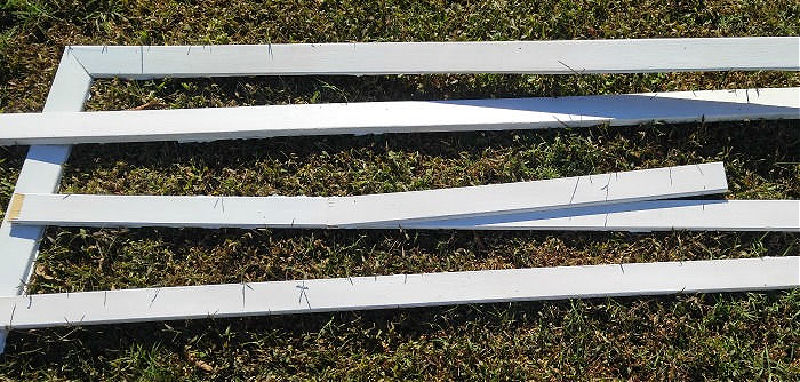 Wooden pieces of an old door frame painted white on a green lawn.