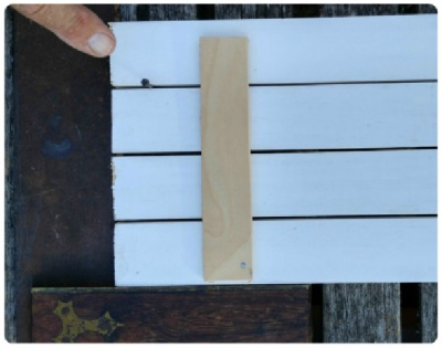 Four pieces of wood with a nail showing how to space them, and a brace on the back.