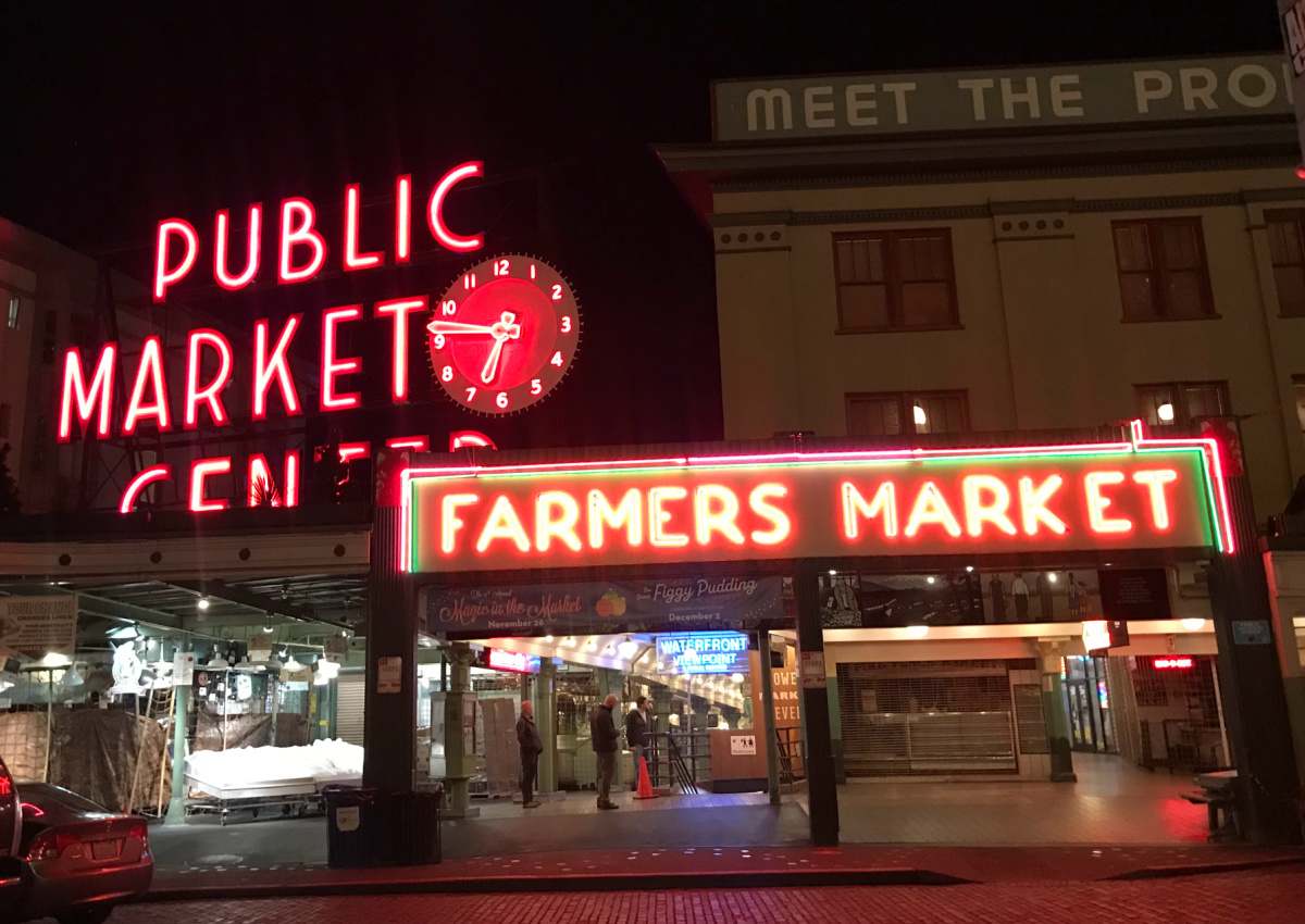 Pike Place farmers market The outside view of the Pike Place Farmer's Market at night, where the signs are lit up.